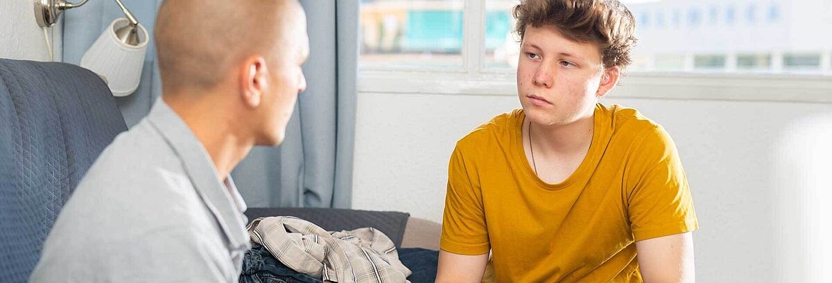 Vater diskutiert mit seinem Sohn im Wohnzimmer