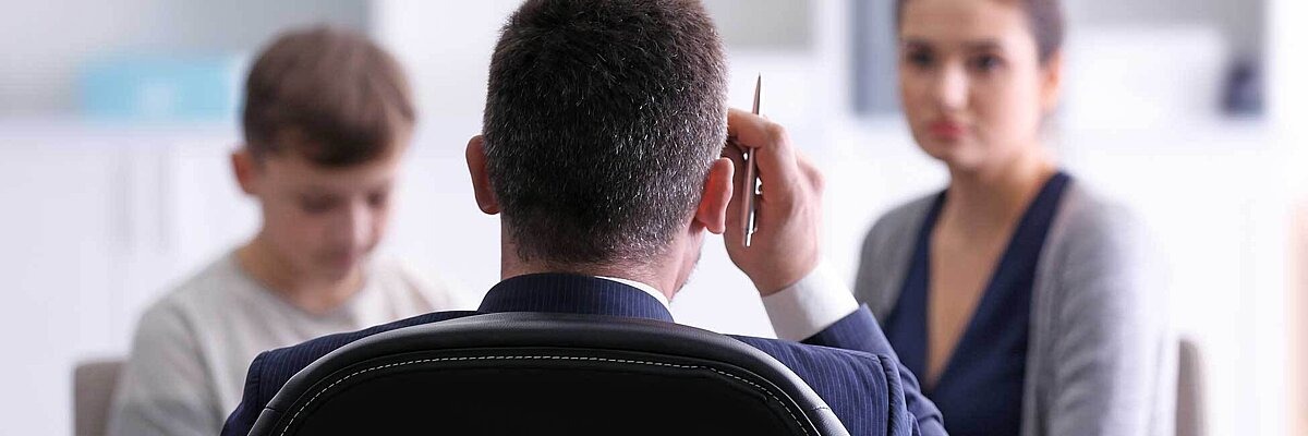 Nahaufnahme eines Lehrers von hinten, der mit einer Mutter und ihrem Sohn spricht