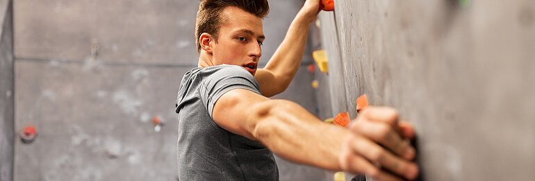 Junger Mann an Kletterwand