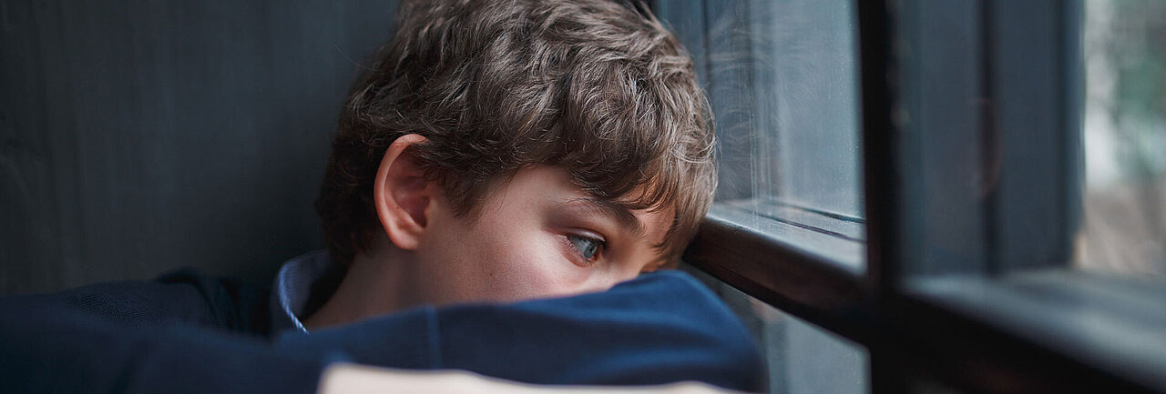 Depremierter Jugendlicher blickt aus dem Fenster