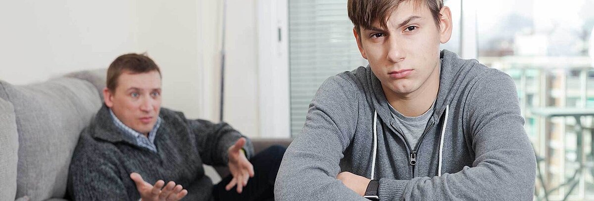 Frustrierter Jugendlicher dreht seinem Vater den Rücken zu