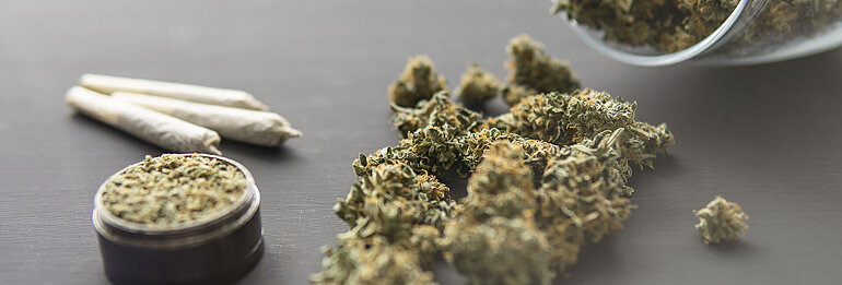 Ansammlung von Joints und getrockneten Cannabisblüten auf einem Tisch