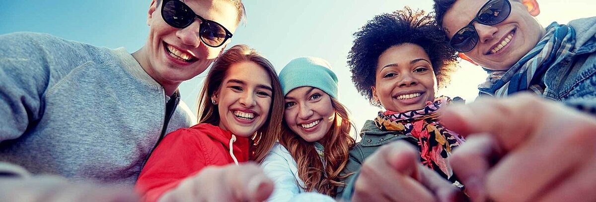 Fünf diverse Teenager zeigen mit Fingern auf die Kamera