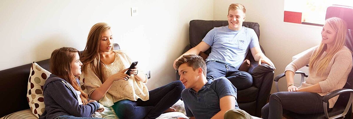 Fünf diverse Teenager entspannen auf Sofas im Raum