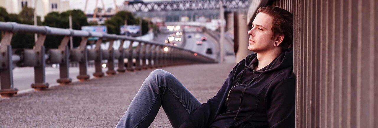 Teenager auf einer Brücke lehnt sich ans Gelände