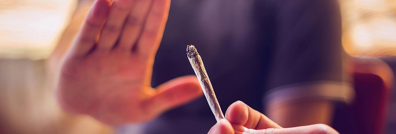 Die Nahaufnahme einer Hand, die den ihr angebotenen Joint zurückweist.