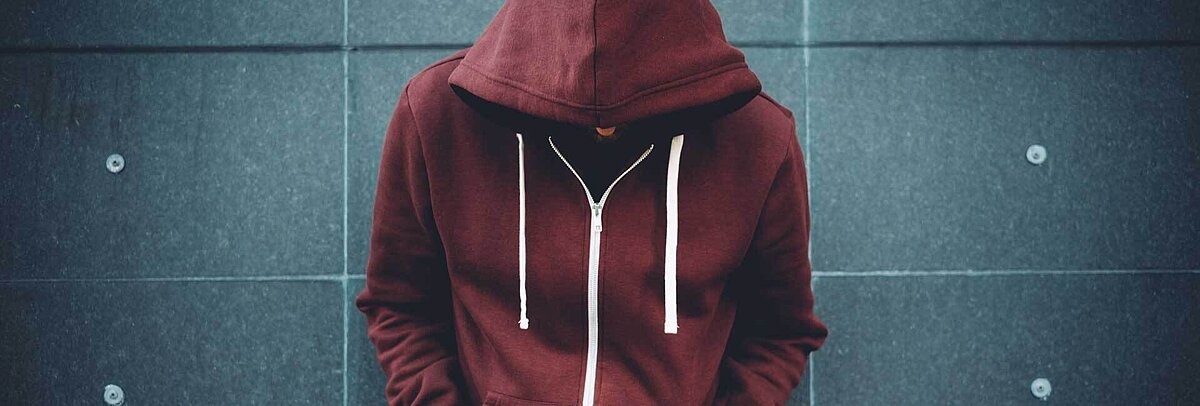 Teenager mit rotem Hoodie und gesenketm Kopf