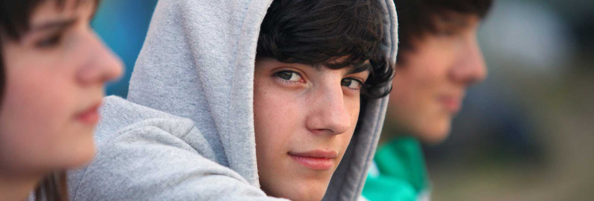 Cannabis: Risiken für Jugendliche Nahaufnahme eines Jugendlichen in grauem Hoddie, der nachdenklich in die Kamera schaut