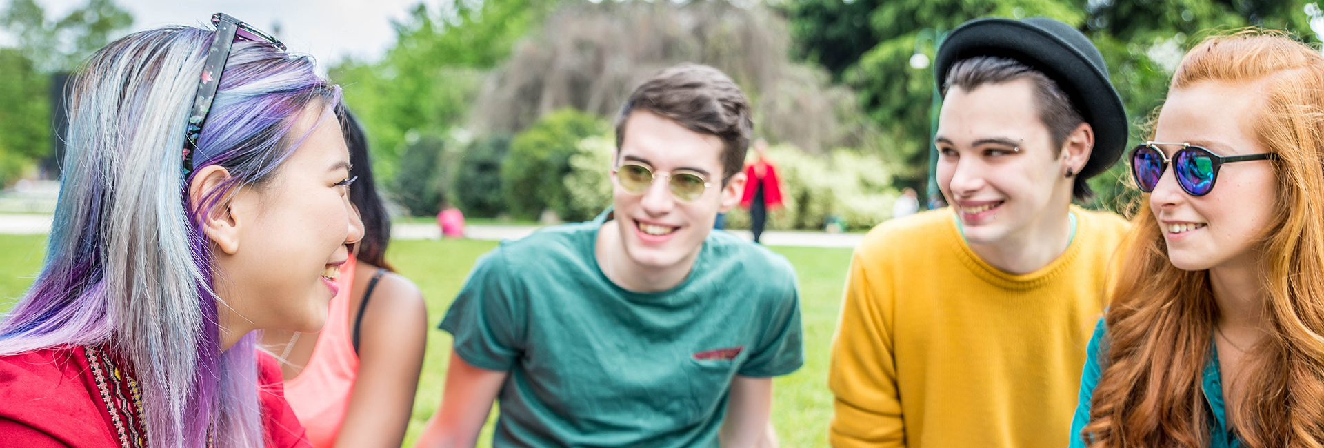 Vier diverse Jugendliche in bunten Outfits im Park