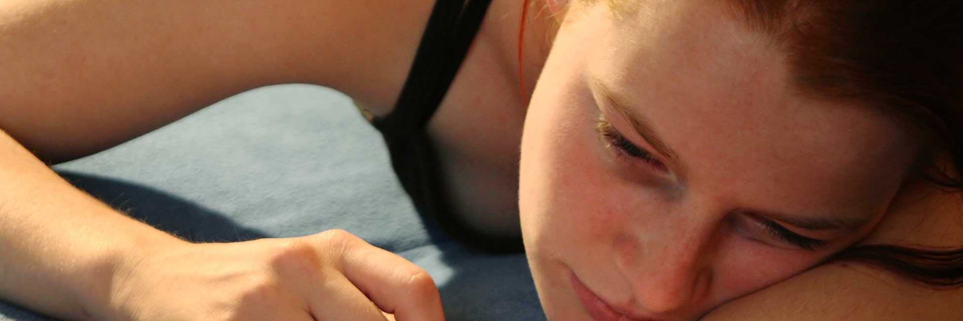 Nahaufnahme einer Teenagerin, die deprimiert auf dem Bauch liegt