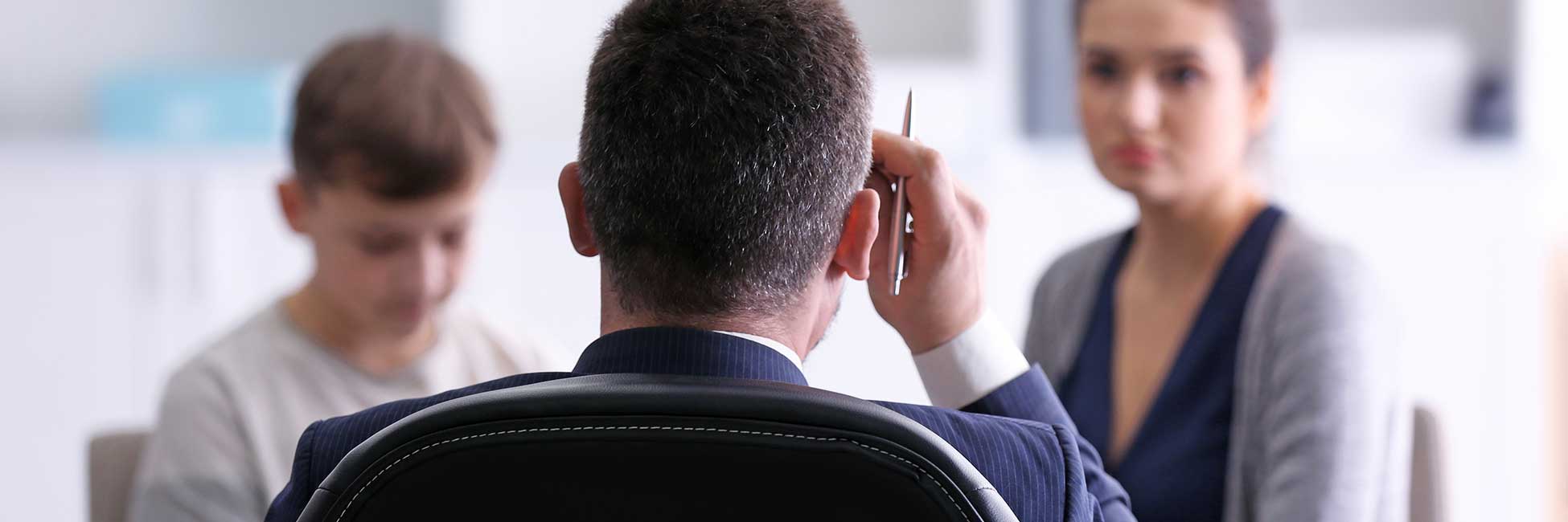 Nahaufnahme eines Lehrers von hinten, der mit einer Mutter und ihrem Sohn spricht